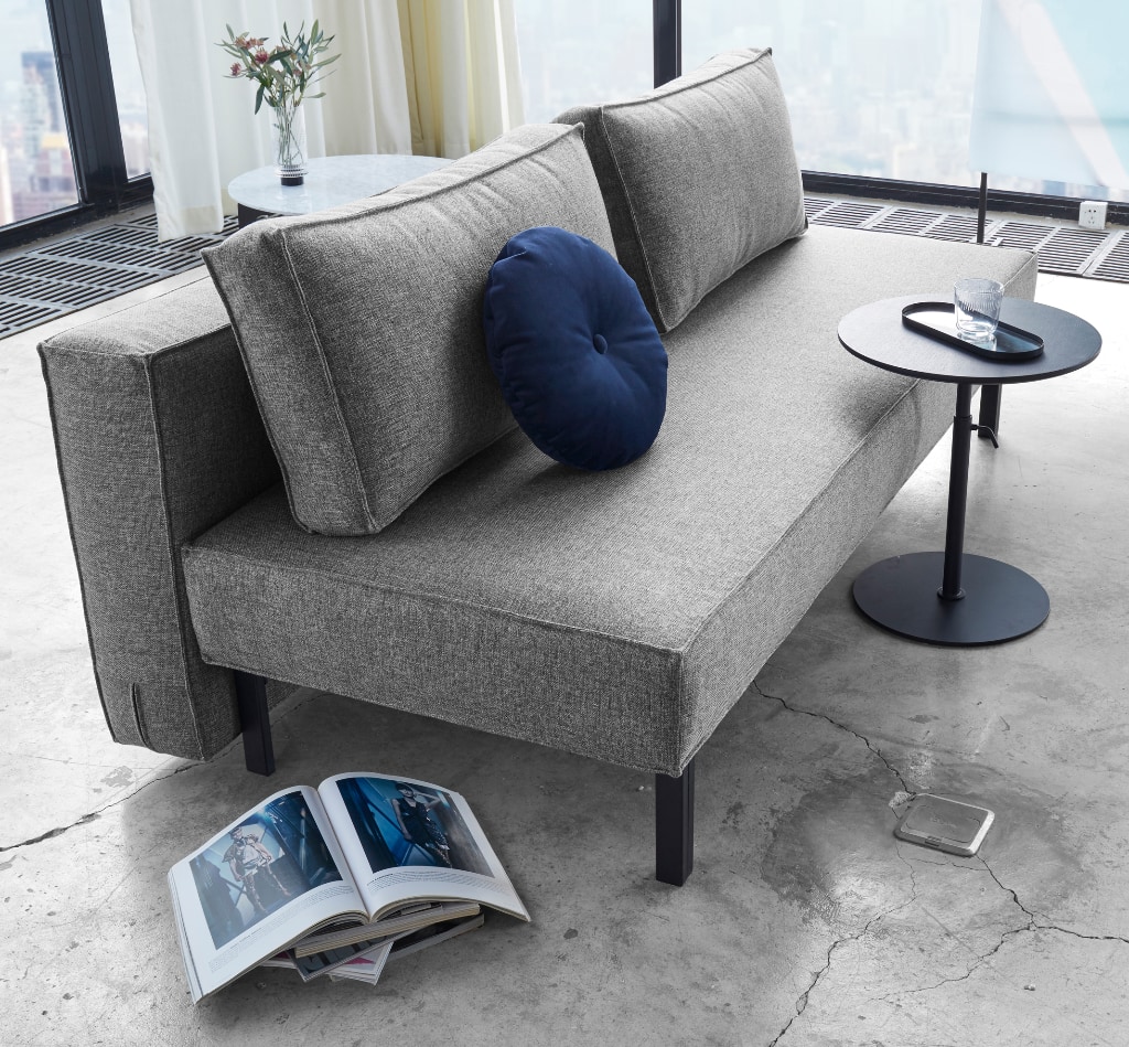 Sly bäddsoffa klädd i tyg 563 Twist Charcoal, som soffa tillsammans med Kiffa sidobord